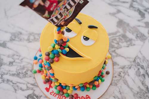 birthday cake M&M pack pouring candies on M&m cake's mouth on marble surface cake
